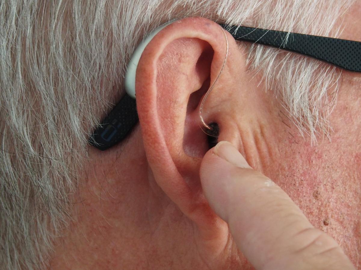 Close up of ear with hearing aid and glasses.