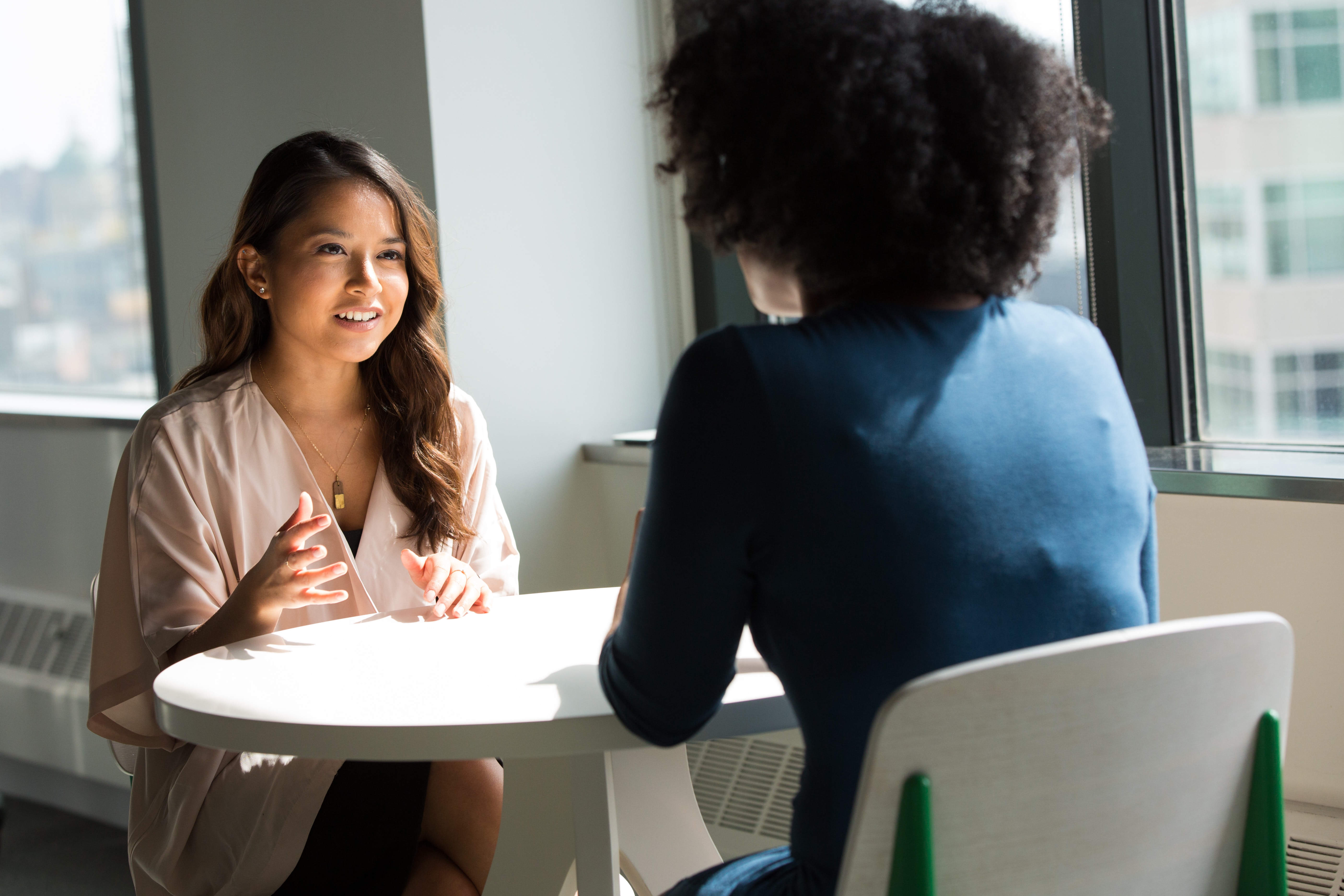 Two woman chatting at a table.
